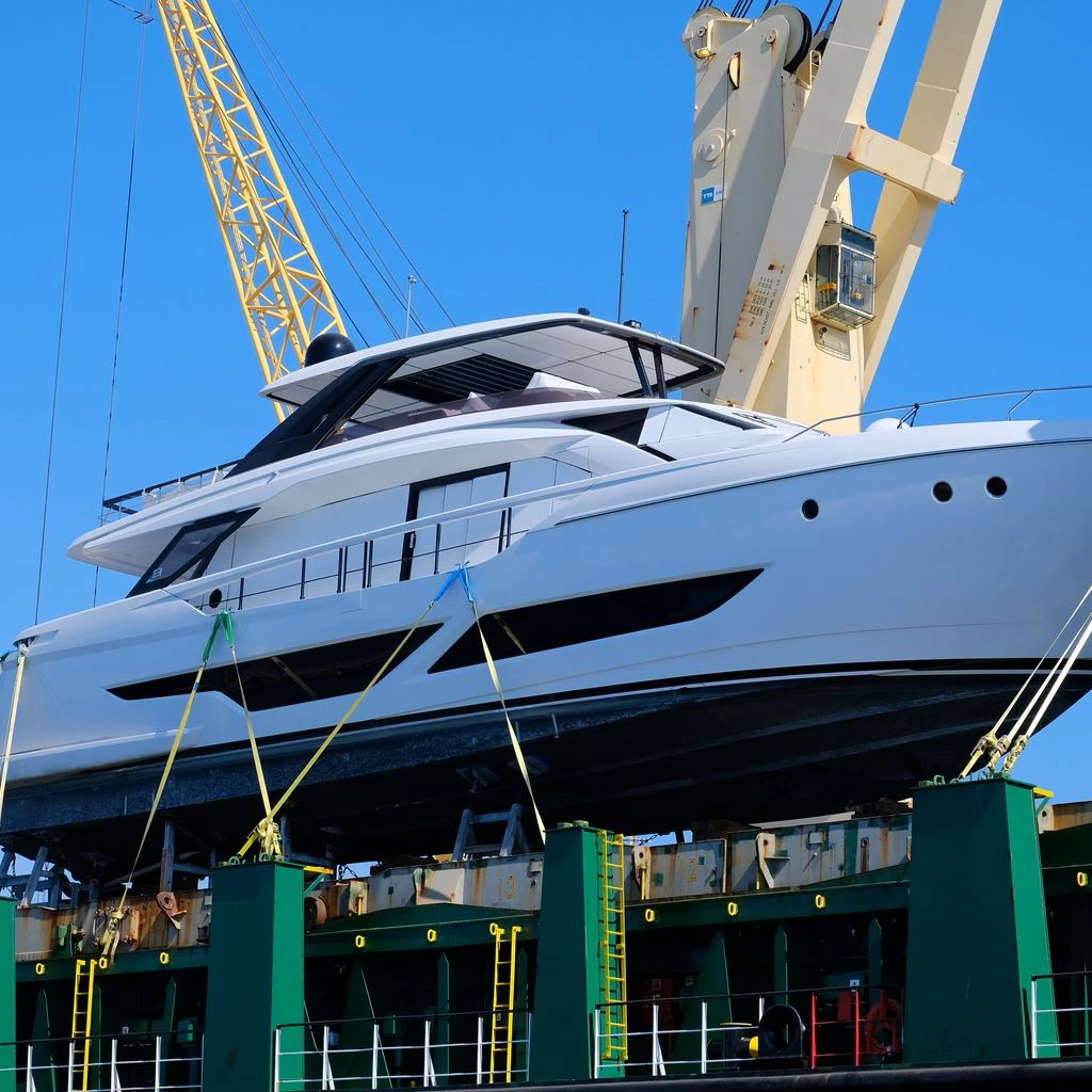 A yacht mid-haul by the 70-tonne travelift beside the 42 m heated refit hall at Gdańsk Marine Center.